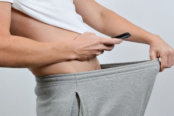 bir adam pantolonunun altından büyümüş penise bakıyor